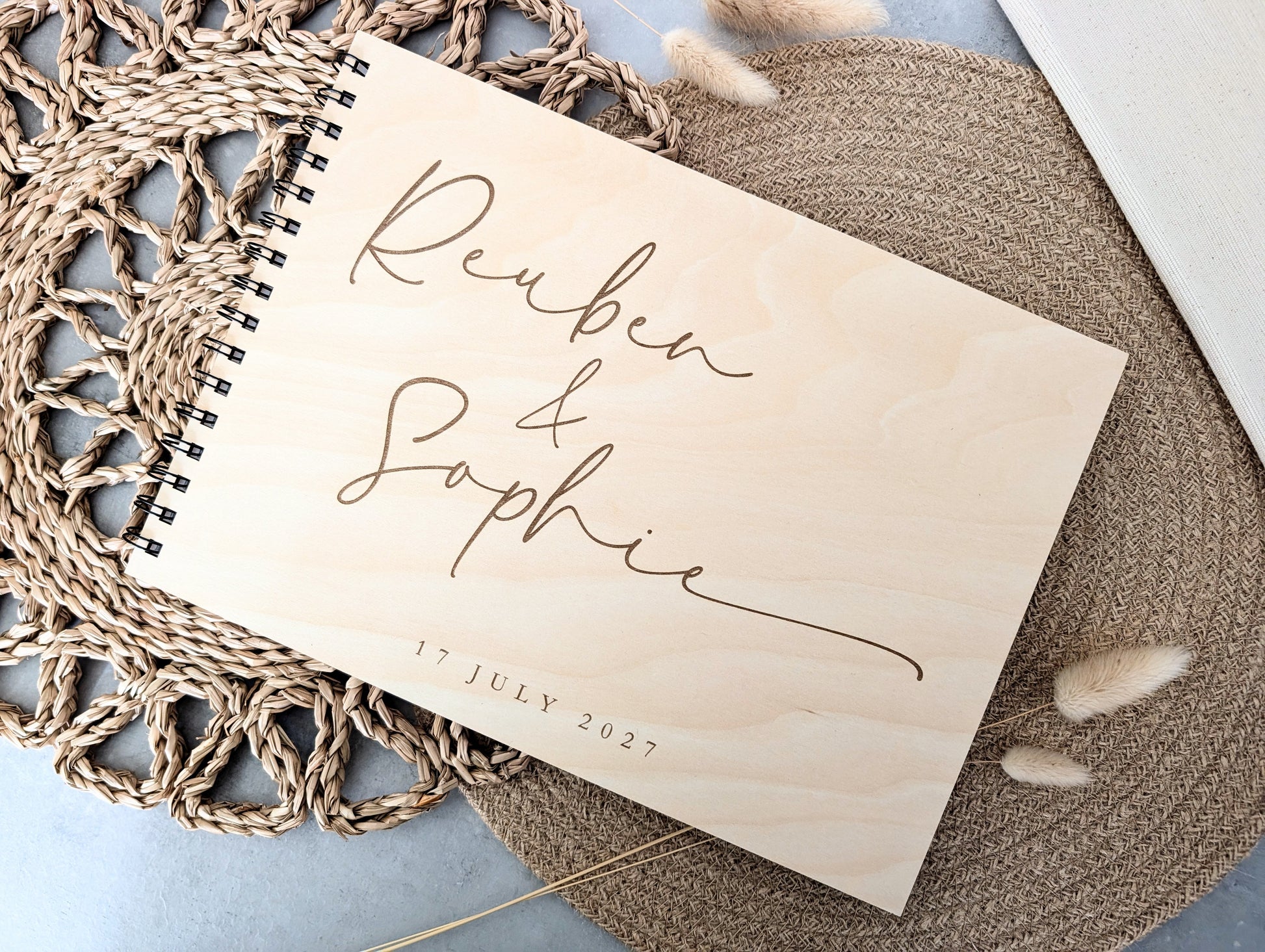“Personalised wooden wedding guest book engraved with surname and date”

“Engraved basswood guest book with spiral binding”

“Rustic wooden wedding guest book on woven mat”